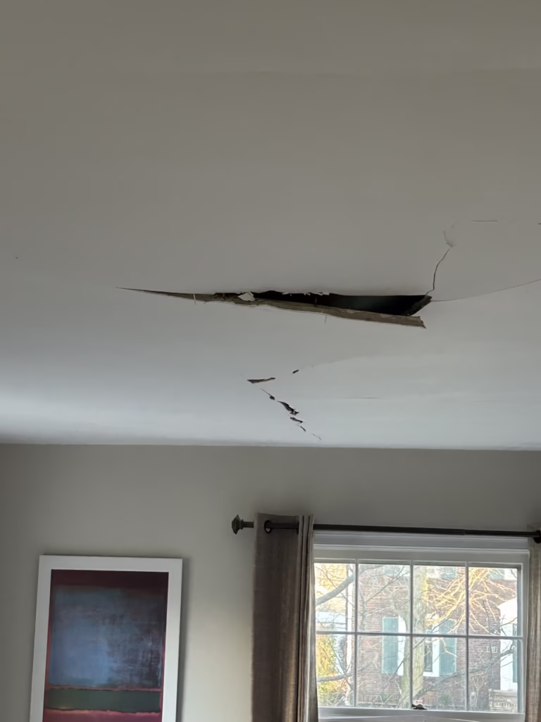 Rocklath plaster ceiling with section hanging loose and visible hole above, photographed hours before full collapse in Deerhurst Park, Kenmore NY