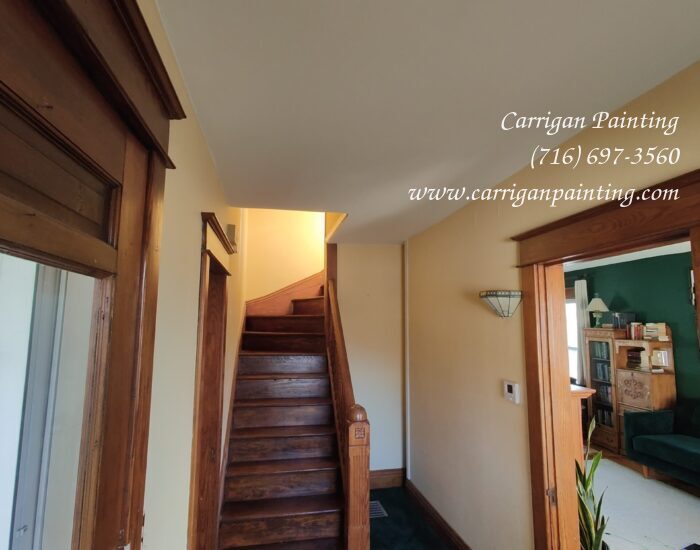 a hallway with stairs and green carpet