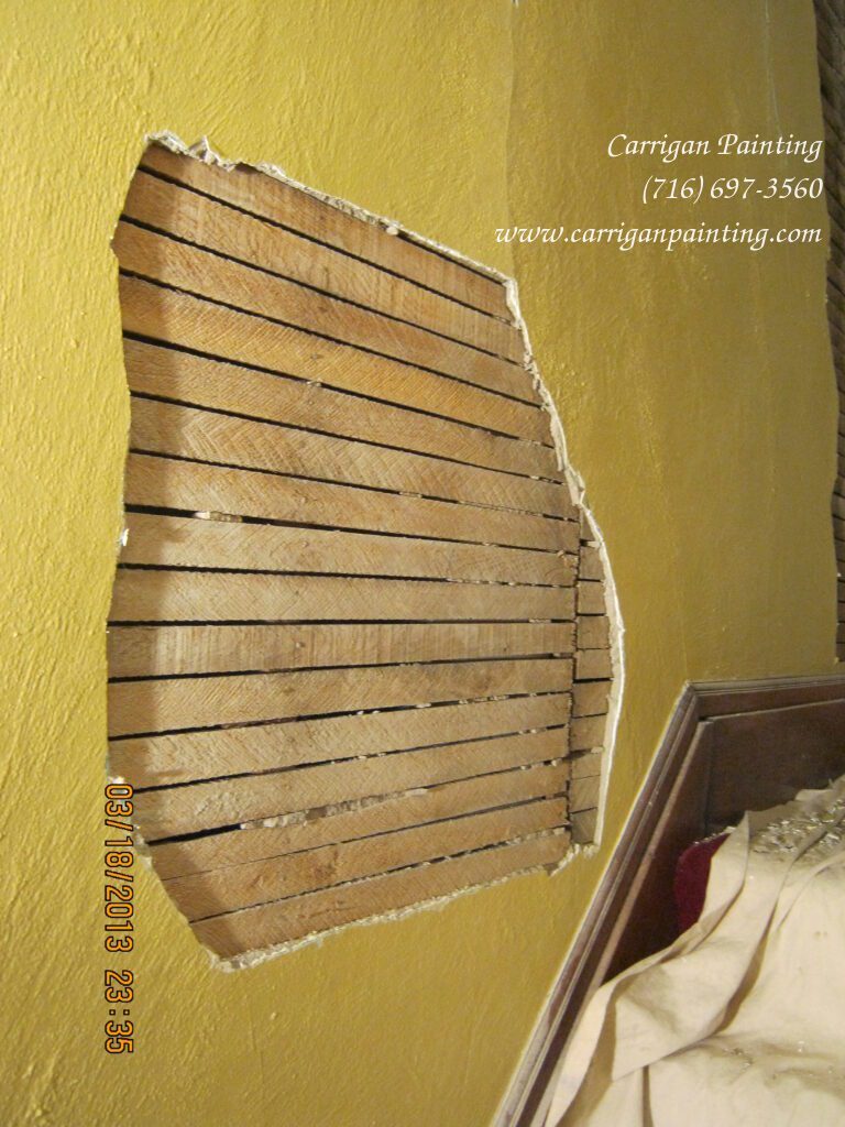 wood-lath exposed in plaster wall