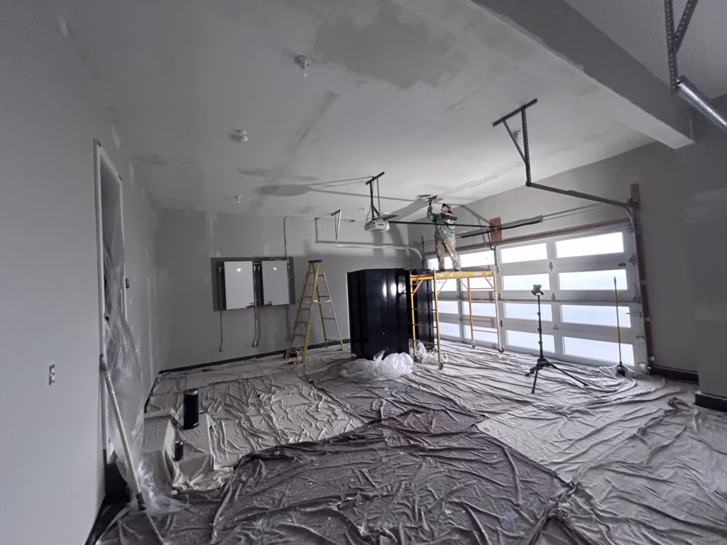 A female worker patching a garage ceiling while standing on scaffolding.