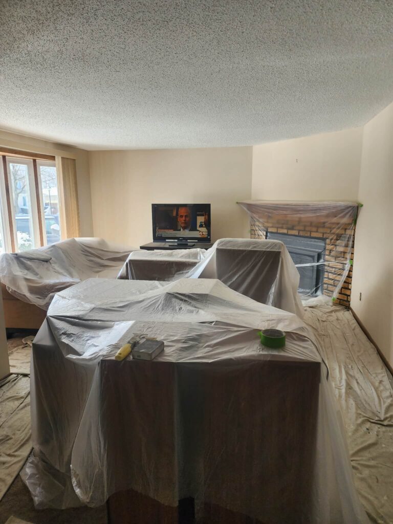living room covered in plastic, and prepped for painting